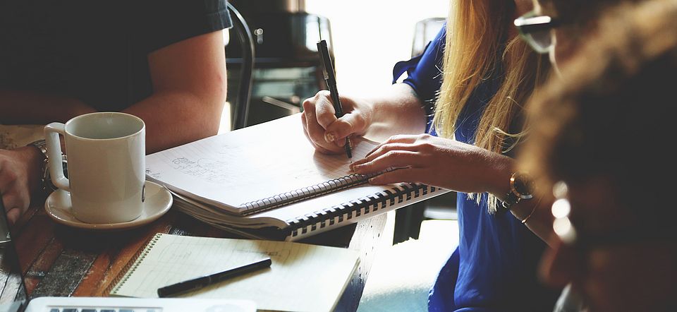 Menschen an Tisch mit Notizblöcken