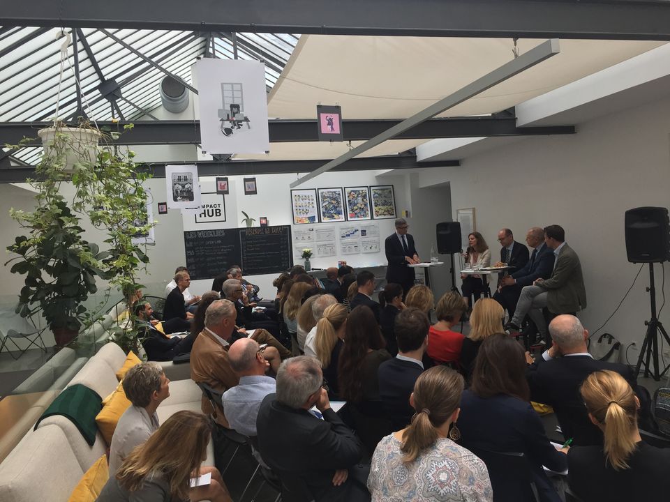 Zuschauer sitzen in hellem Raum und hören einer Podiumsdiskussion zu