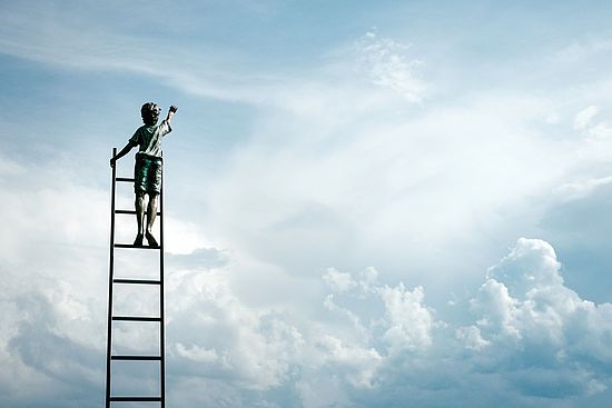 Junge auf freistehender Leiter greift gegen den Himmel
